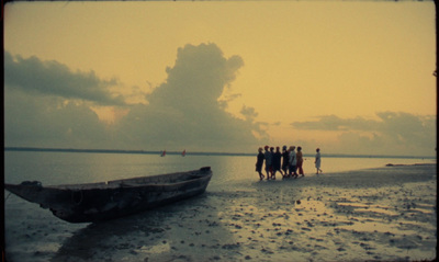 a group of people standing next to a boat on a beach