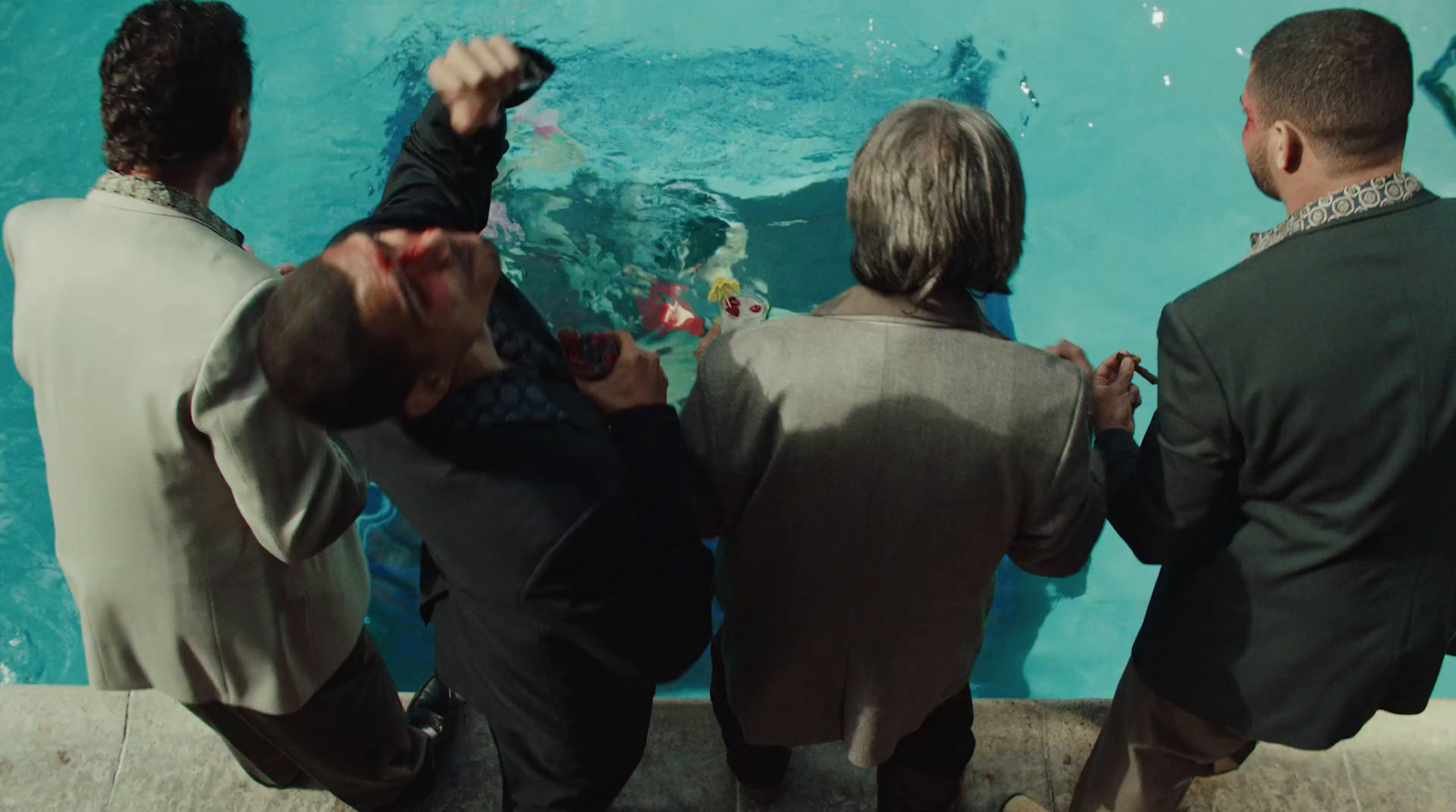 a group of men sitting next to each other near a pool