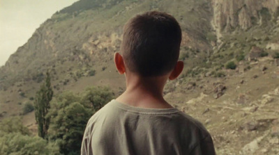 a young man standing in front of a mountain