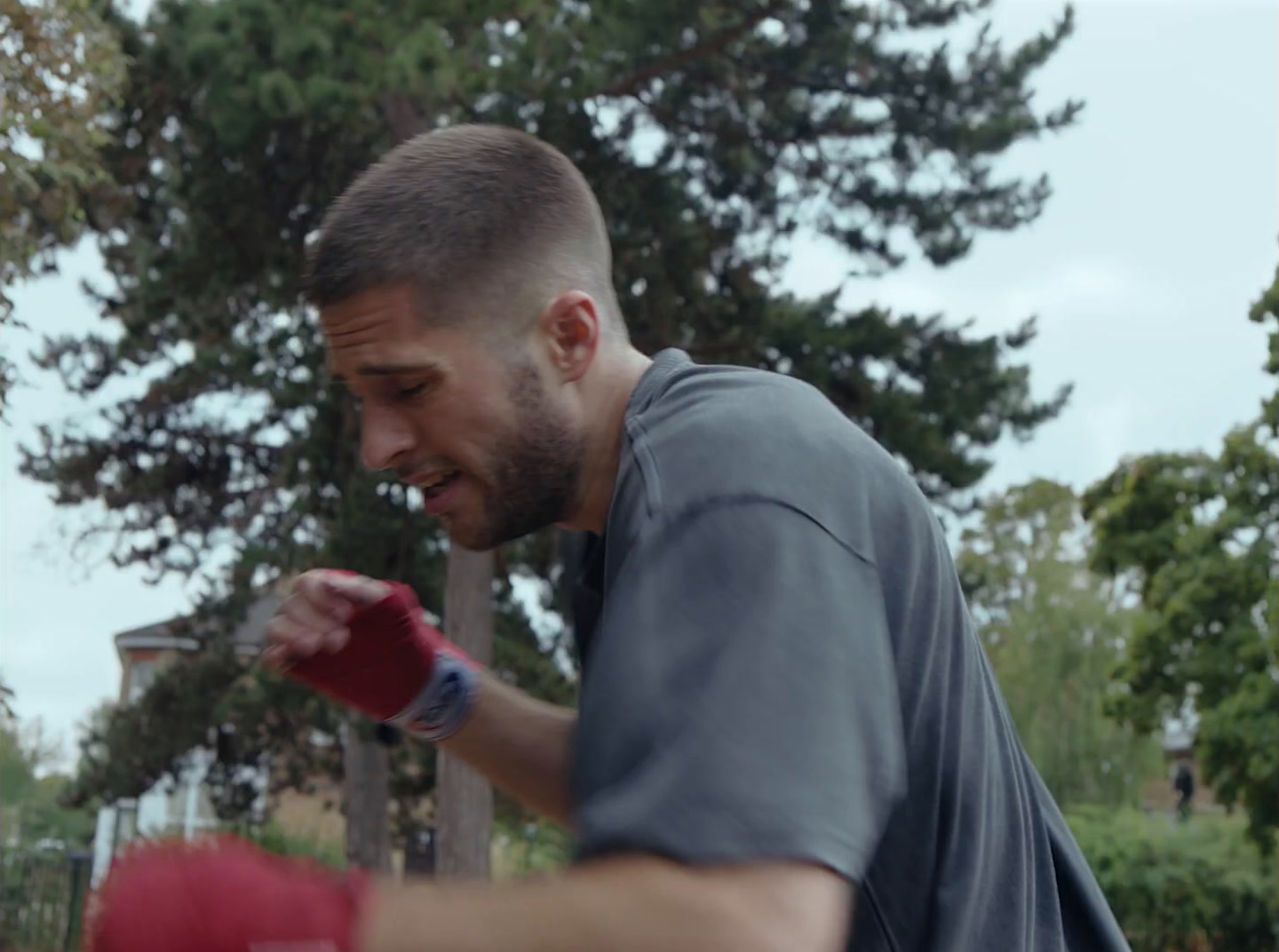 a man wearing a red boxing glove in a park