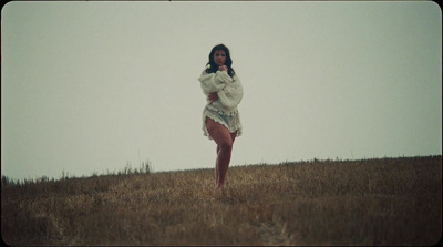 a woman standing in a field with a cell phone