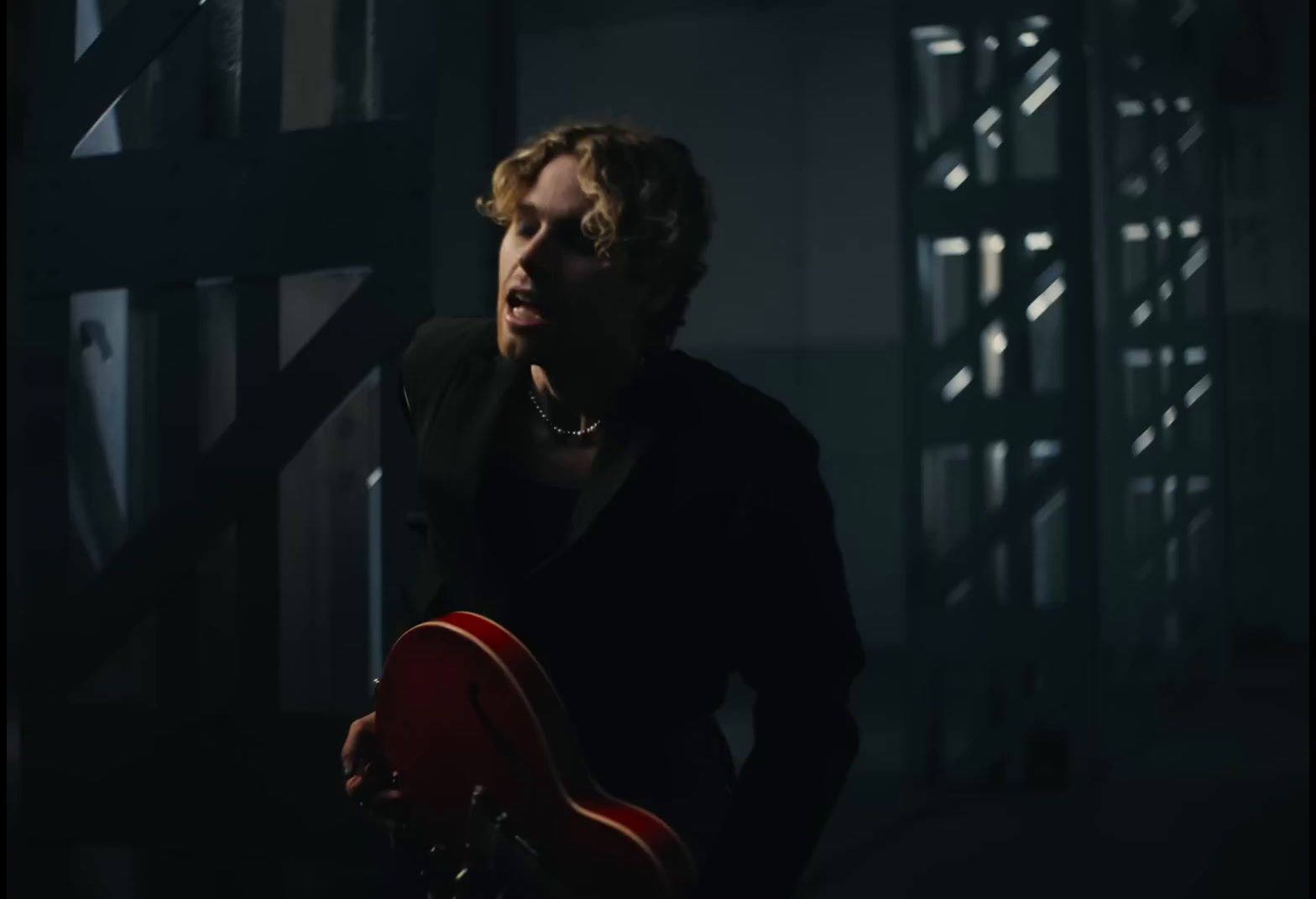 a man holding a red guitar in a dark room