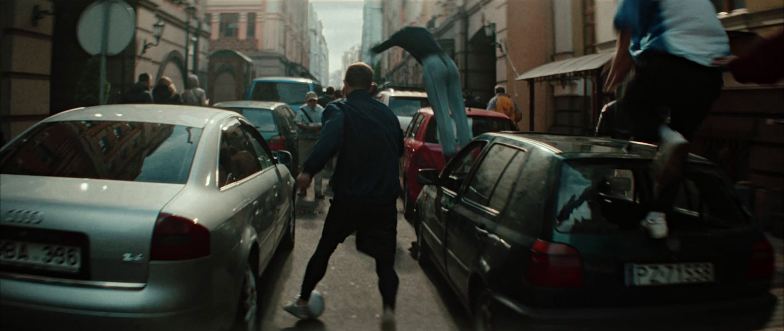 a man walking down a street next to parked cars