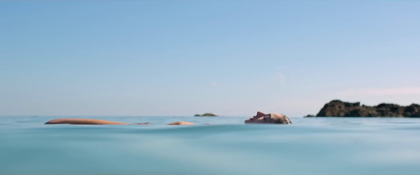 a woman floating in the ocean with her head above the water