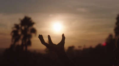 a person reaching up to the sun with their hands