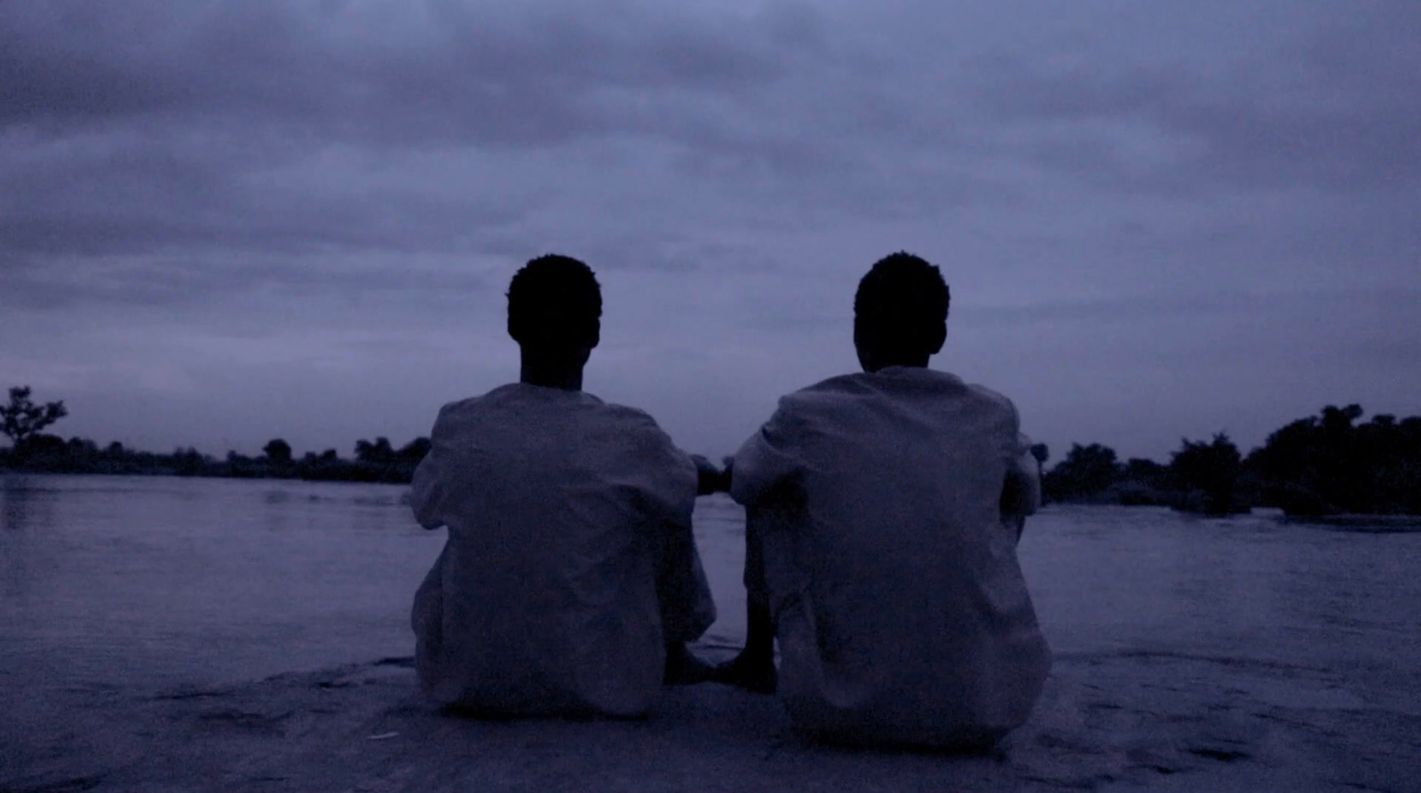 two people sitting on a beach in the dark