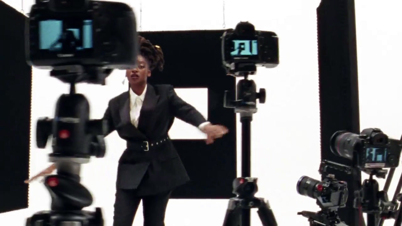 a woman standing in front of a bunch of cameras