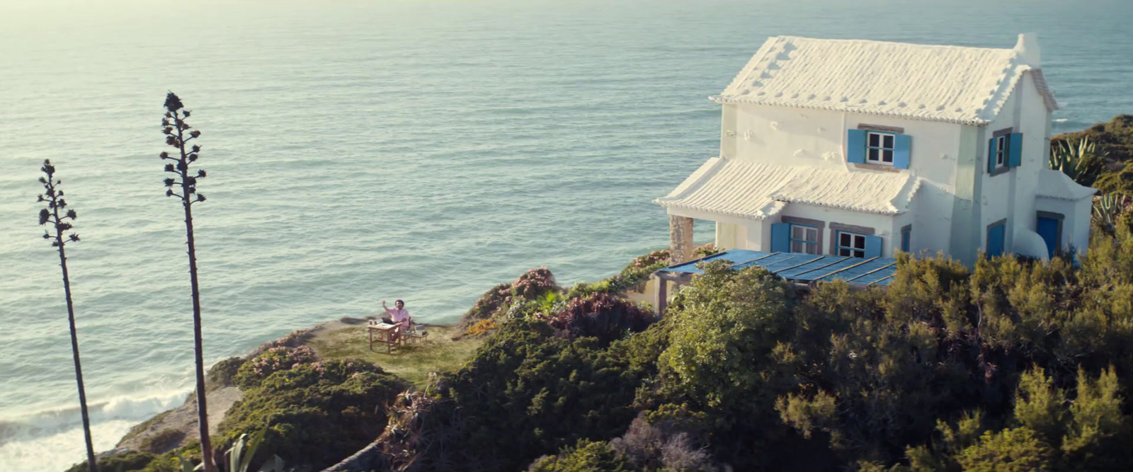 a house sitting on top of a hill next to the ocean