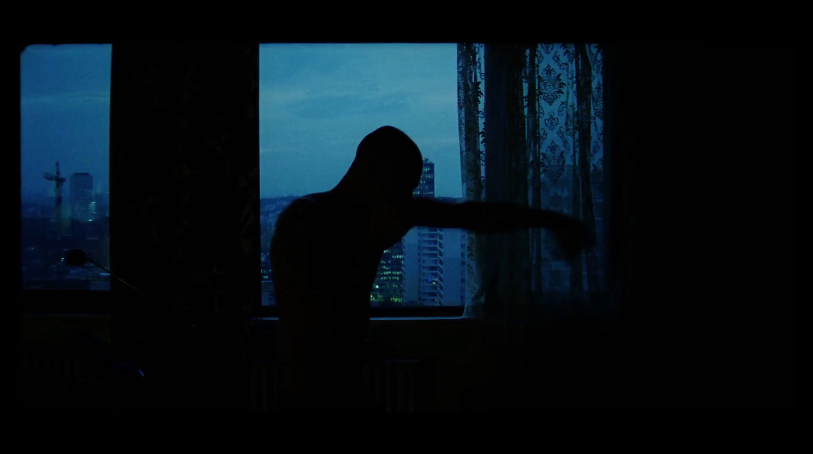 a person standing in front of a window in the dark