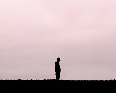 a person standing on a hill with a kite in the sky