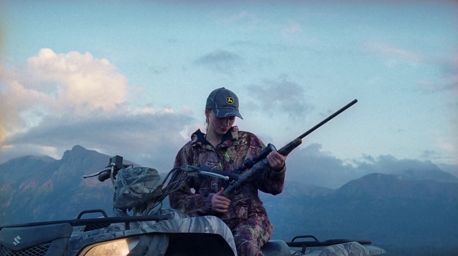 a man holding a rifle while sitting on an atv