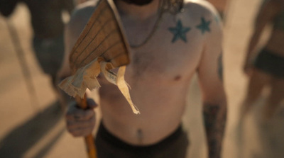 a shirtless man with no shirt holding a wooden stick