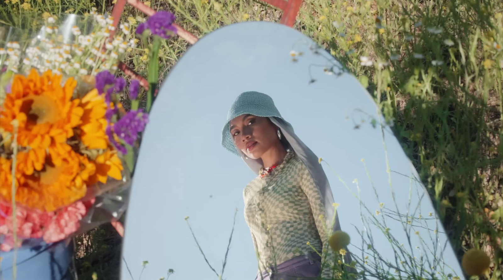 a woman standing in front of a mirror in a field of flowers