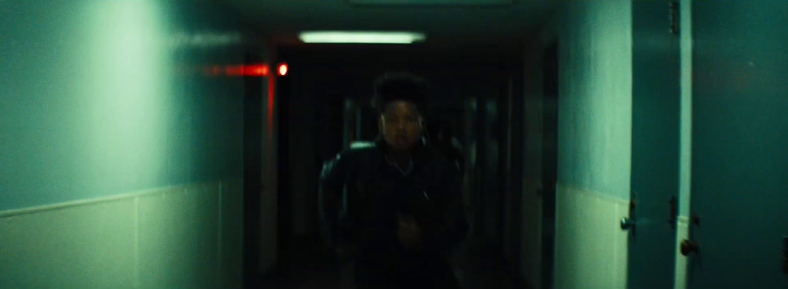 a man walking down a hallway in a dark room