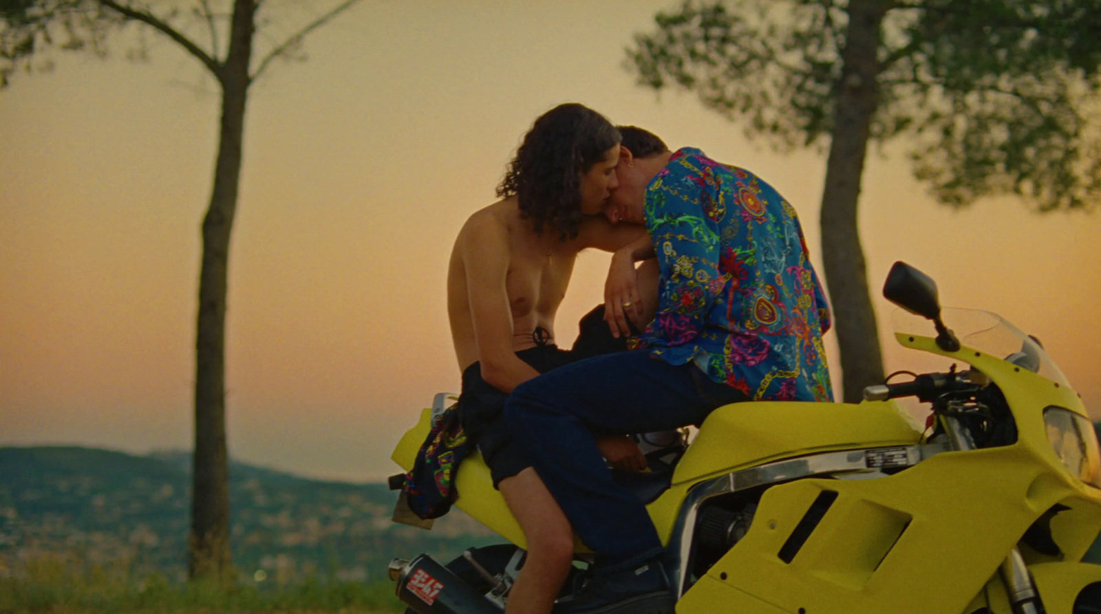 a man and a woman kissing on a yellow motorcycle