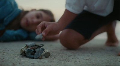 a little girl laying on the ground next to a pile of rocks