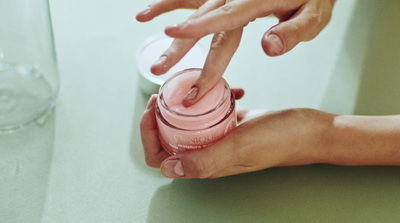 a person is holding a jar with a pink substance in it