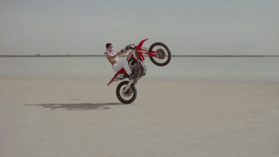 a man riding a motorcycle on top of a sandy beach