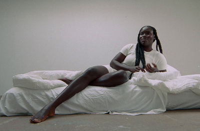 a woman sitting on top of a bed covered in white sheets