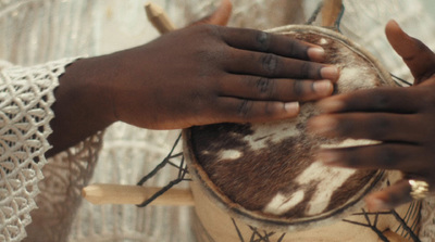 a woman is playing a drum with her hands