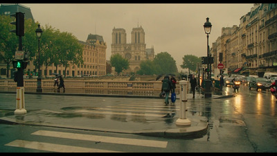 a rainy day in a city with people crossing the street