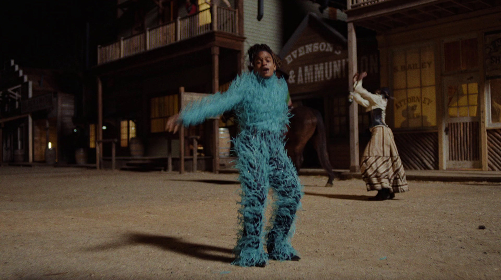 a woman in a blue feathered outfit standing in front of a building