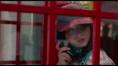 a woman talking on a cell phone in front of a red phone booth