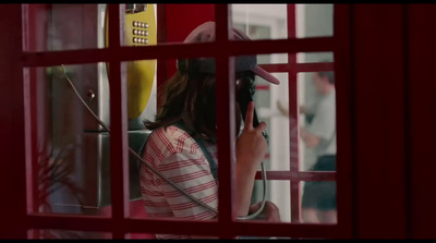 a woman standing in front of a red phone booth