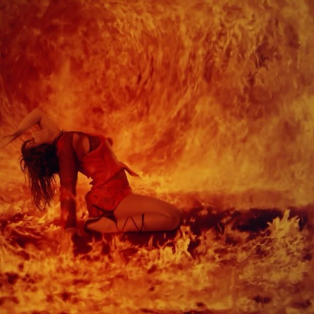 a woman in a red dress is dancing in a fire