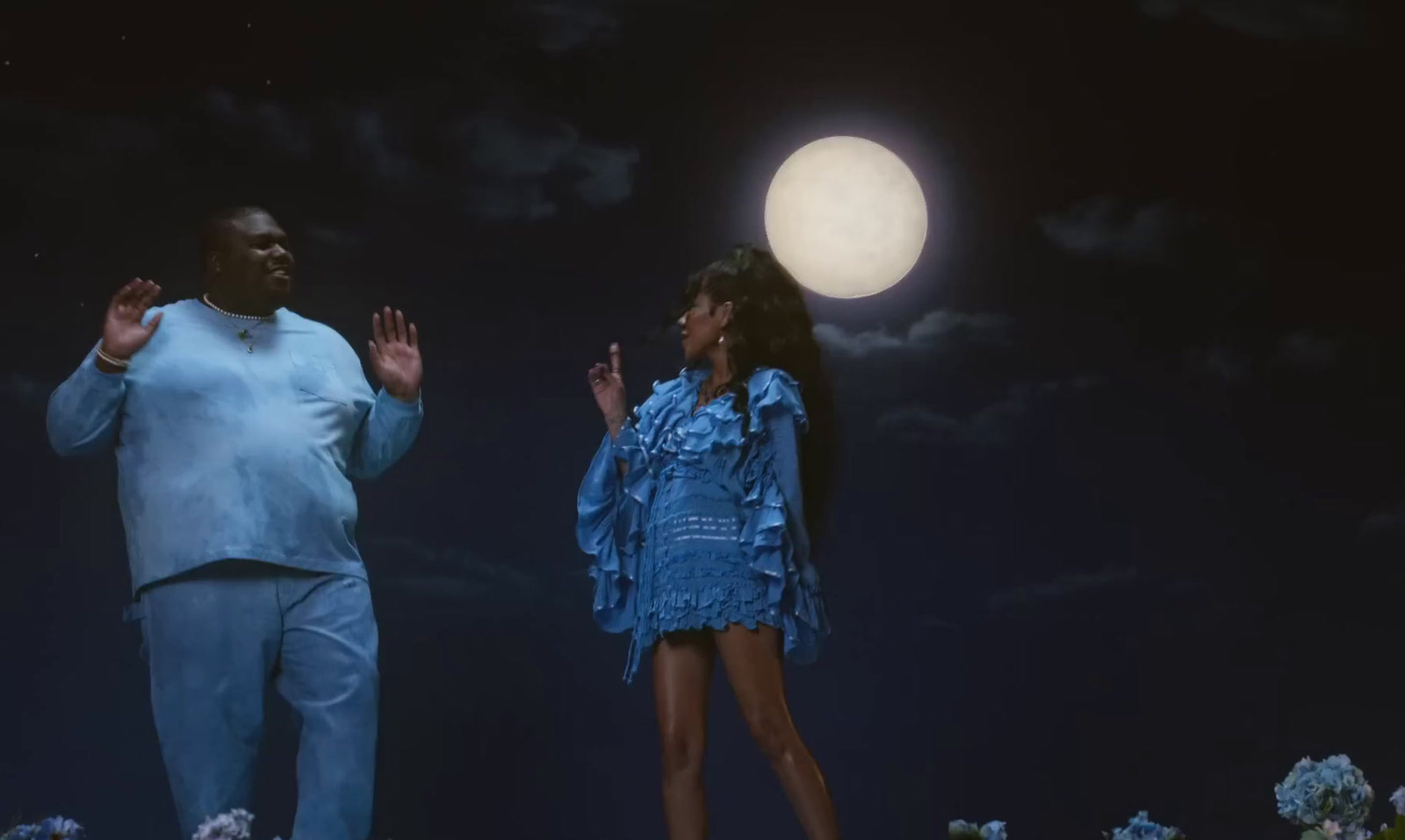 a man and a woman standing in front of a full moon