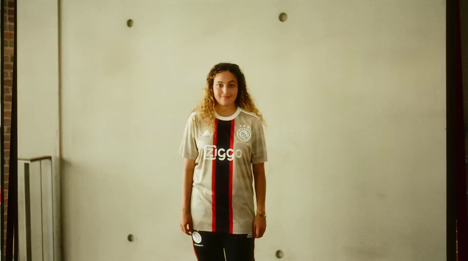 a woman standing in front of a wall with a soccer jersey on