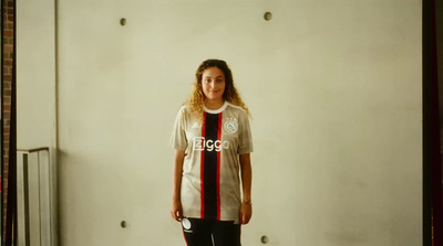 a woman standing in front of a wall with a soccer jersey on