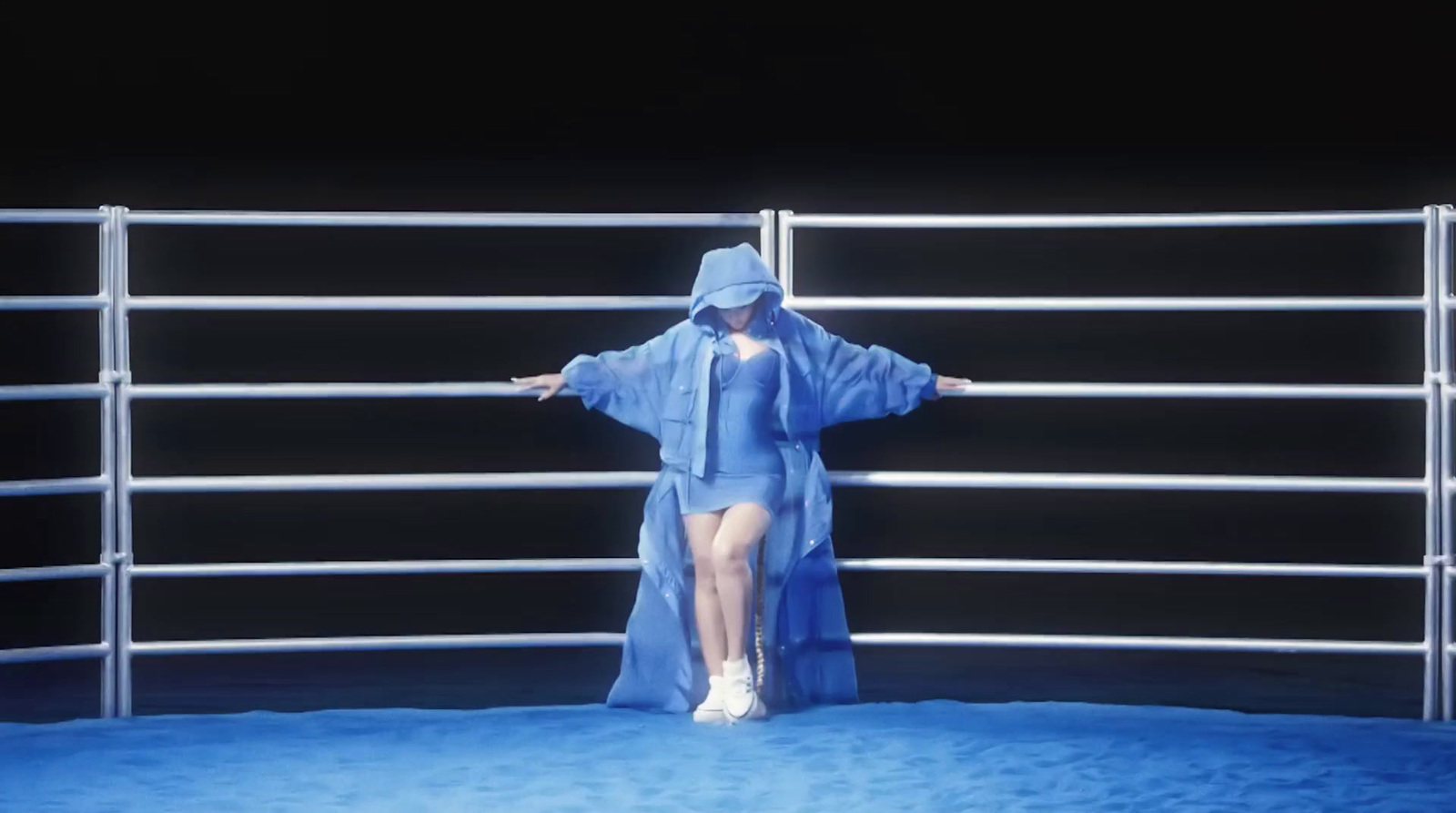 a woman in a raincoat standing in front of a fence