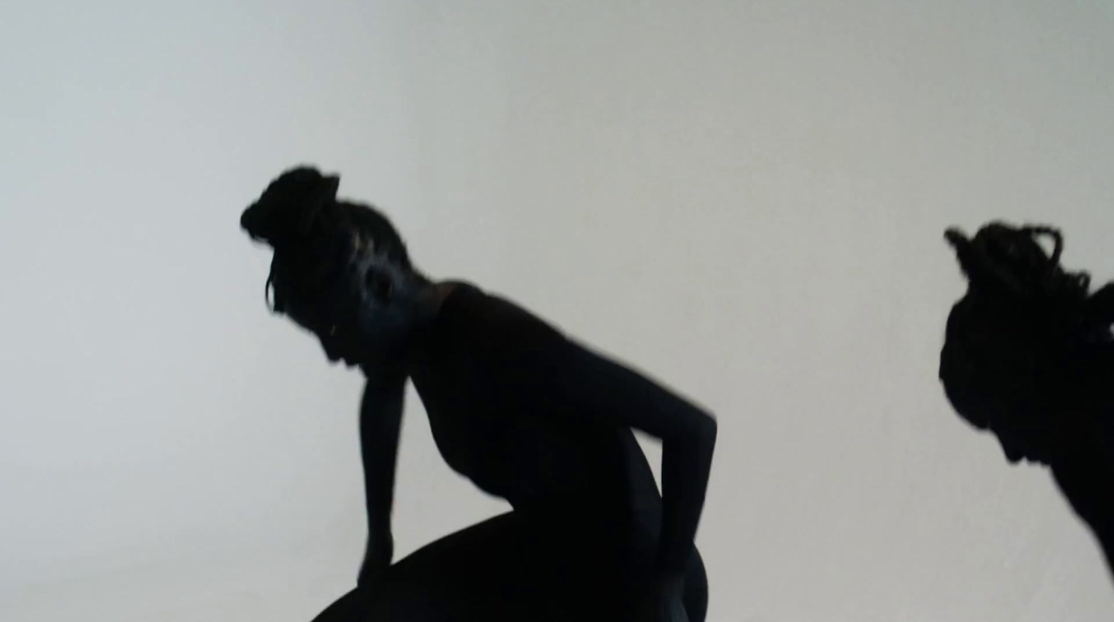 a silhouette of a woman sitting on a stool