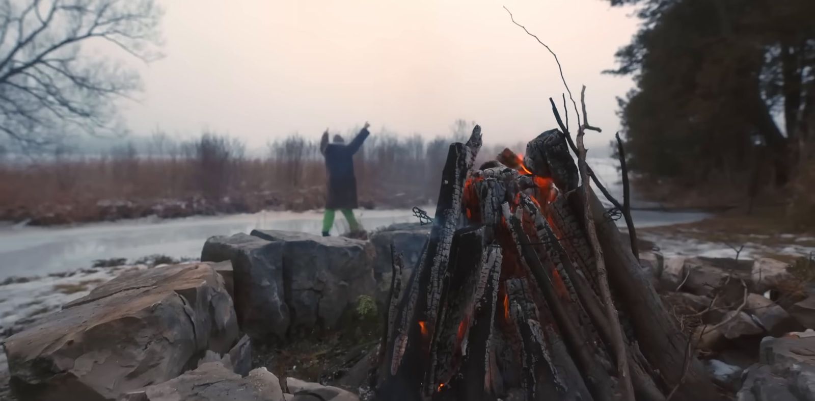 two people standing next to a pile of logs