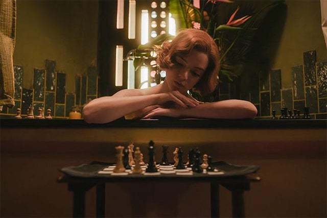 a woman sitting at a table with a chess set in front of her