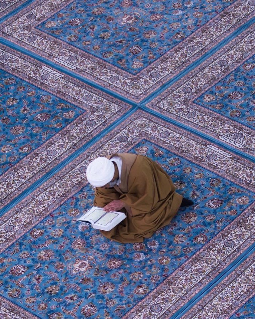 a man sitting on a rug reading a book