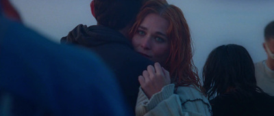 a woman with red hair is hugging a man