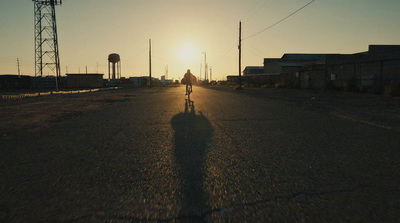 a person riding a bike down a street at sunset