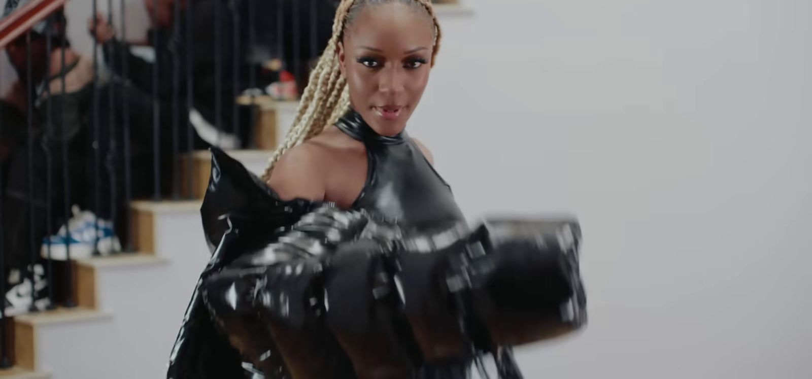 a woman in a black latex outfit holding a camera