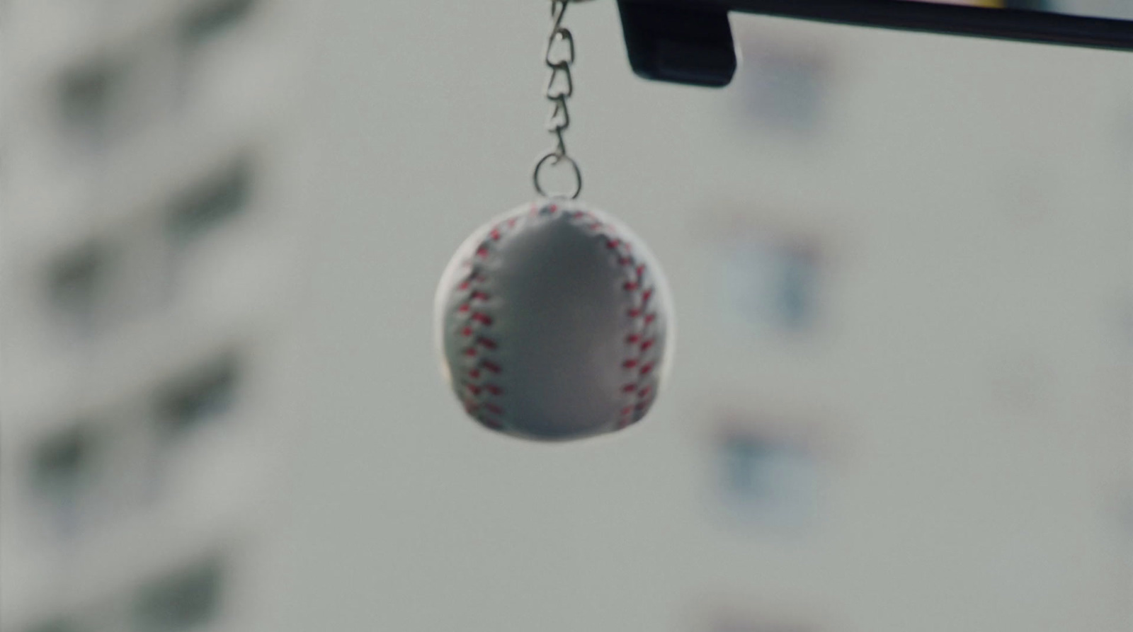 a baseball hanging from a chain in front of a building