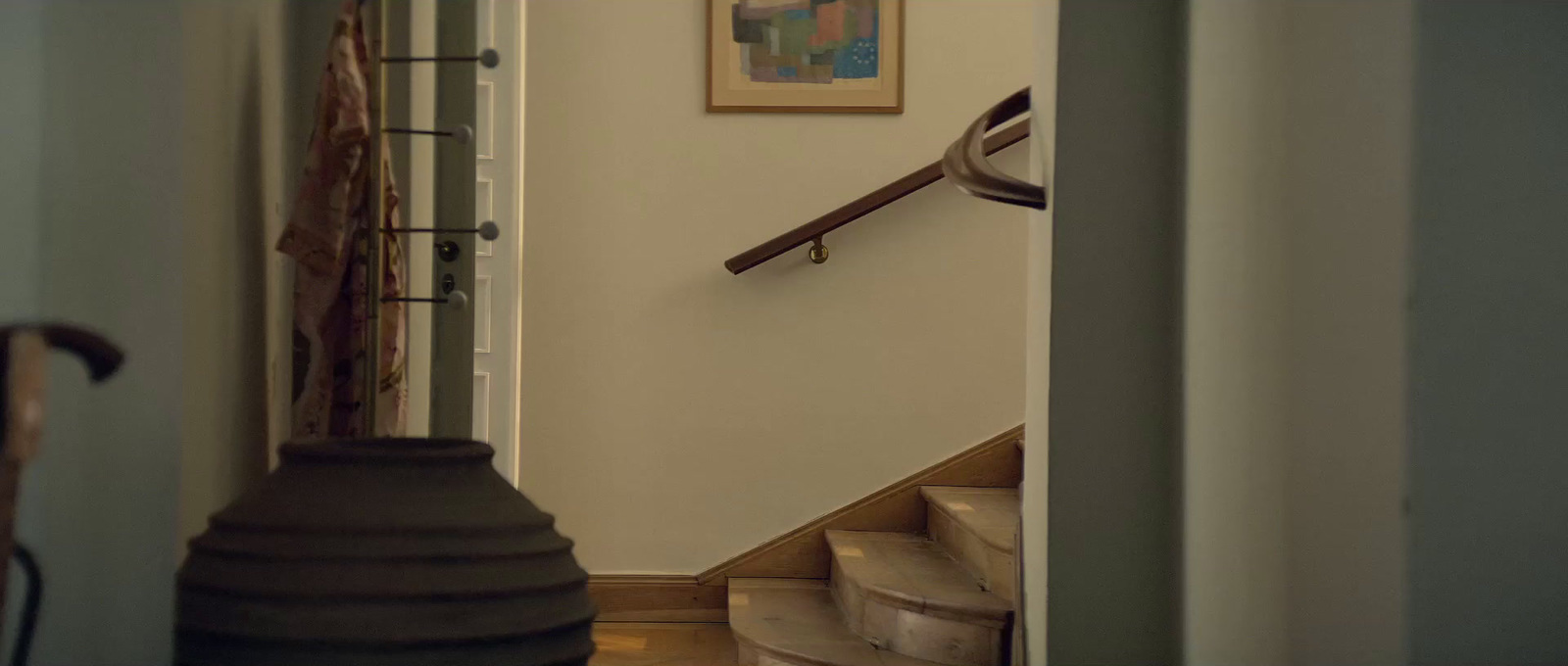 a hallway with a stair case and a painting on the wall