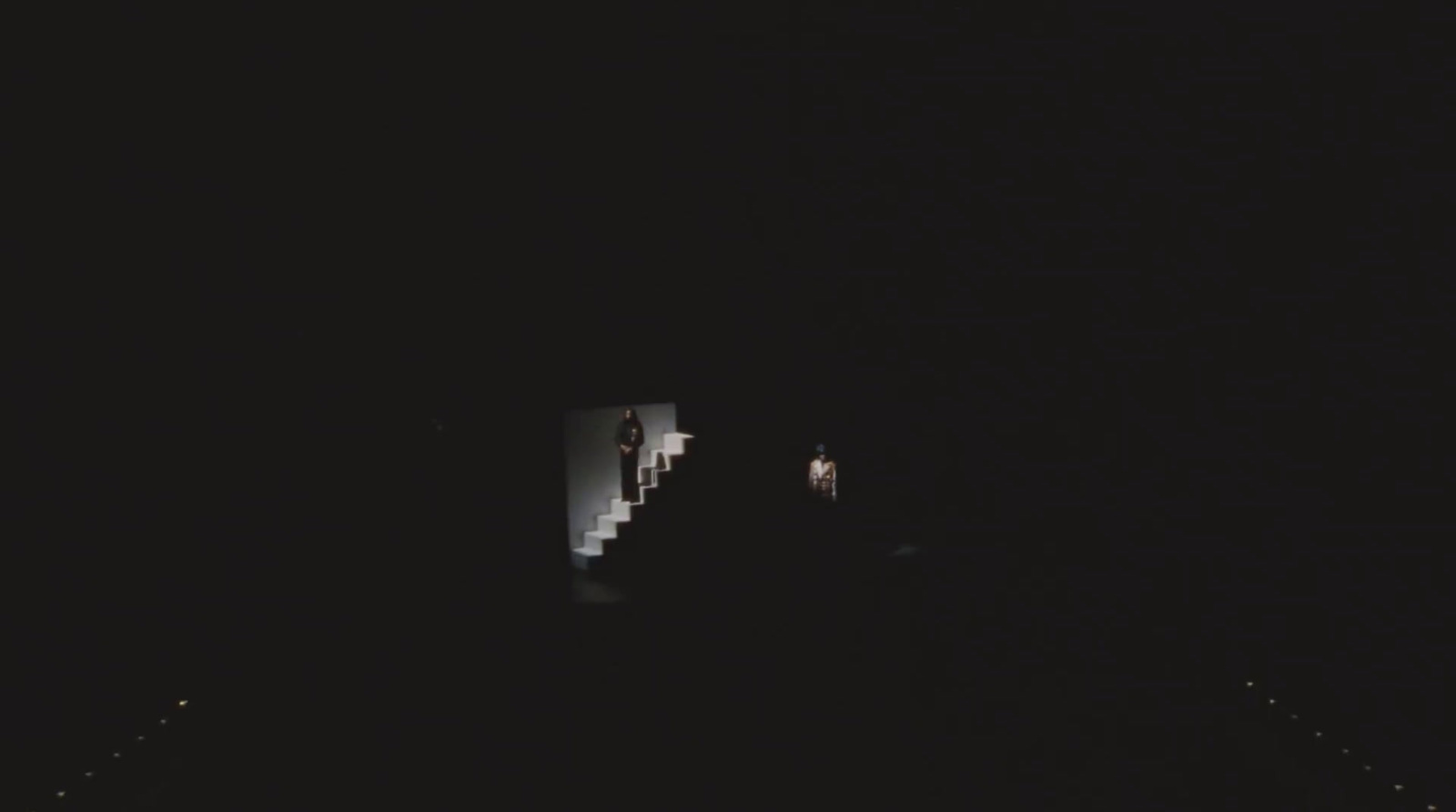 a couple of people standing on a bridge at night