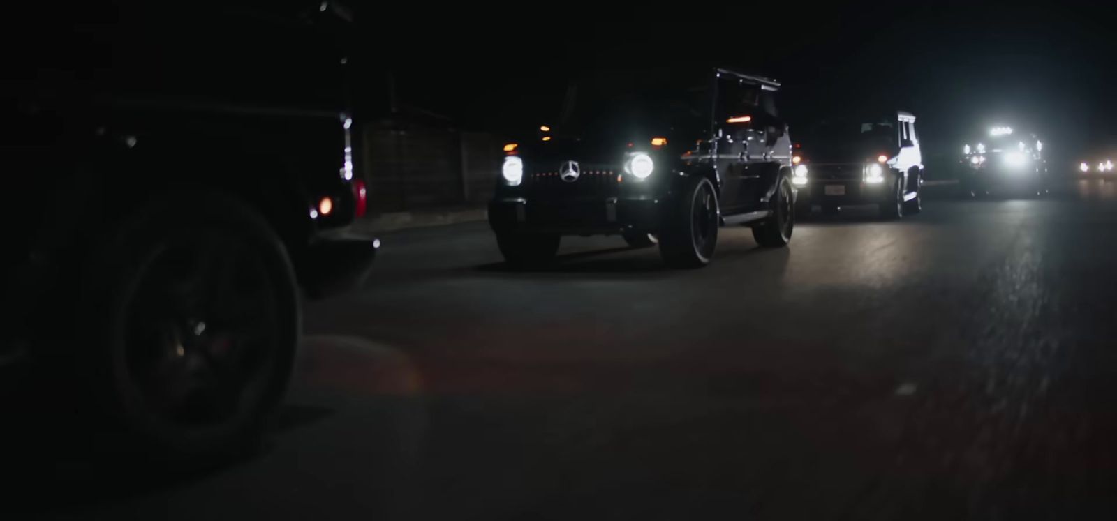 a group of trucks driving down a street at night