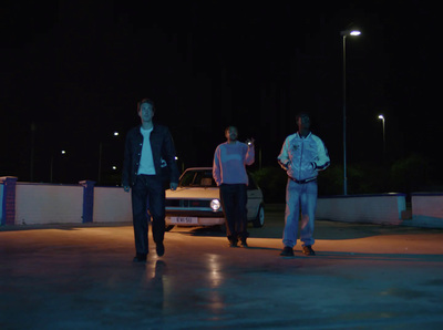 three men standing in front of a car at night