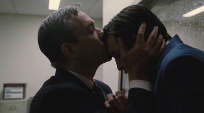 a man in a suit and tie kissing another man