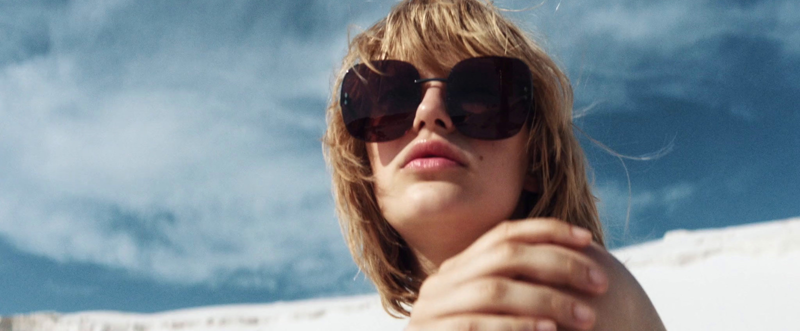 a woman wearing sunglasses and looking up into the sky