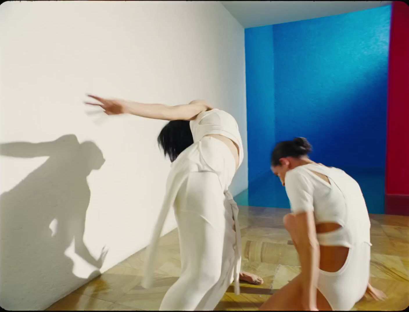 two women in white clothes are standing in a room