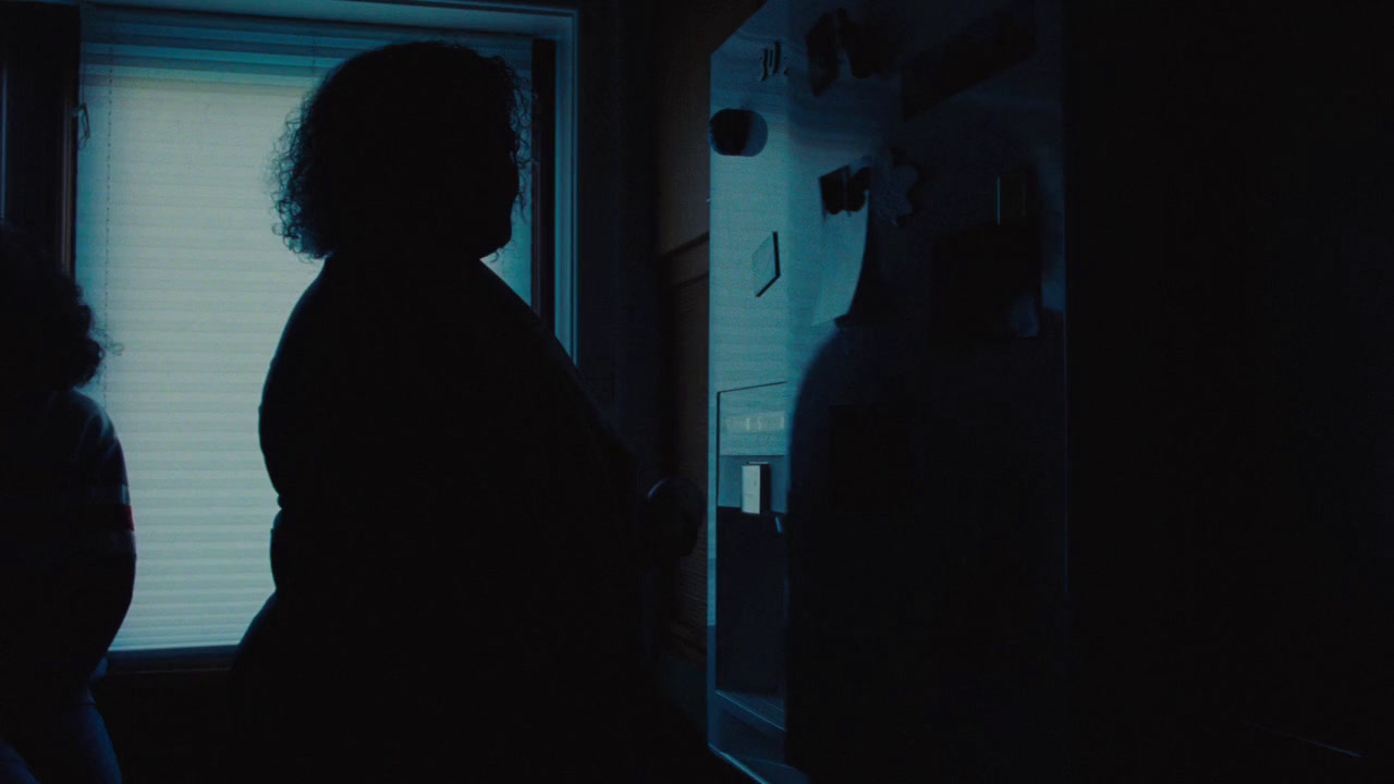 a woman standing next to a window in a dark room