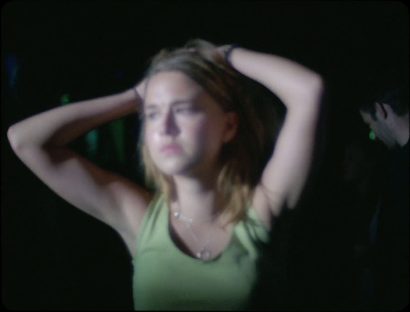 a woman in a green tank top holding her hair